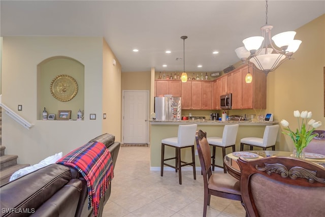 kitchen with kitchen peninsula, hanging light fixtures, stainless steel appliances, and an inviting chandelier