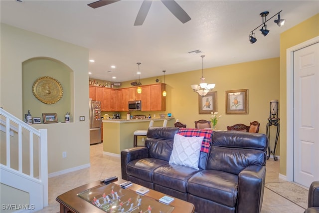 living room featuring ceiling fan with notable chandelier and light tile patterned floors