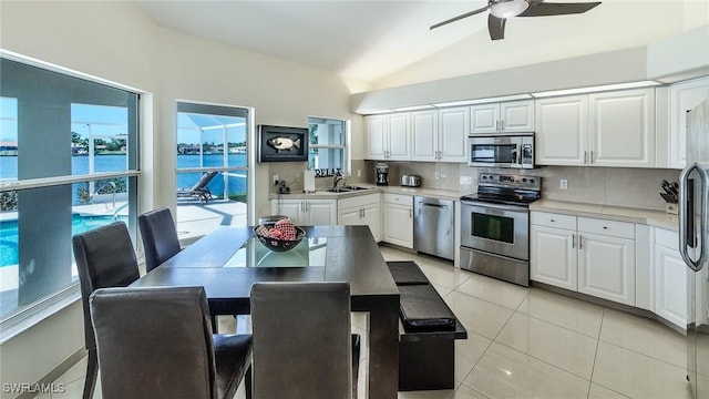 kitchen with vaulted ceiling, appliances with stainless steel finishes, decorative backsplash, sink, and white cabinetry