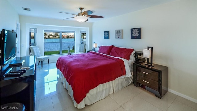 tiled bedroom with ceiling fan and a water view