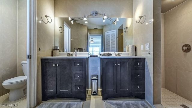 bathroom featuring toilet, tile walls, and vanity