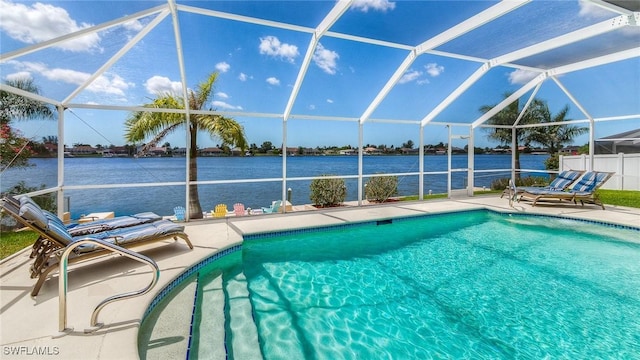 view of pool featuring a patio area, glass enclosure, and a water view