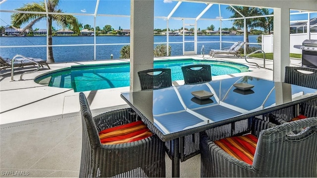 view of pool featuring a patio, glass enclosure, and a water view