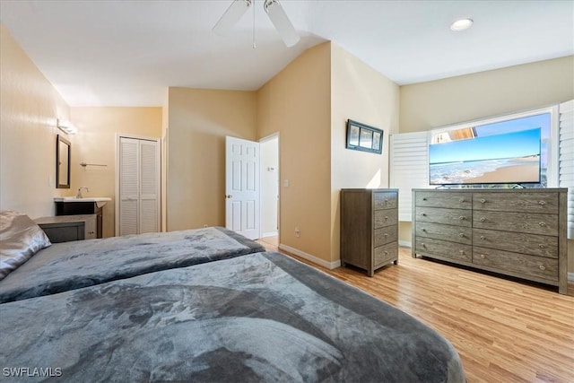 bedroom with ceiling fan, light hardwood / wood-style floors, a closet, and lofted ceiling