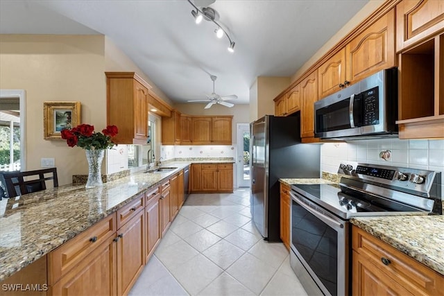 kitchen with sink, light tile patterned flooring, light stone countertops, and appliances with stainless steel finishes