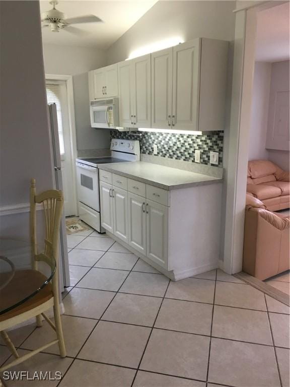 kitchen with white appliances, light tile patterned floors, lofted ceiling, white cabinetry, and ceiling fan