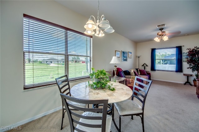 dining space featuring light colored carpet and ceiling fan with notable chandelier