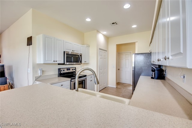 kitchen featuring kitchen peninsula, sink, stainless steel appliances, and white cabinetry