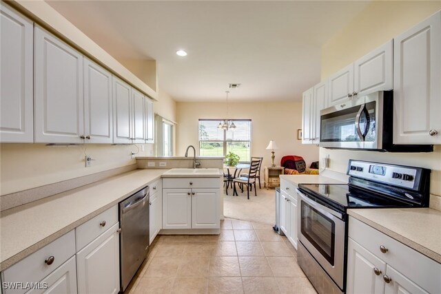 kitchen featuring stainless steel appliances, white cabinets, hanging light fixtures, and sink