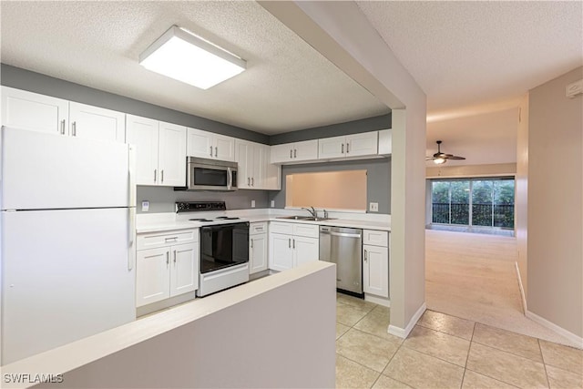 kitchen featuring light tile patterned flooring, appliances with stainless steel finishes, white cabinetry, sink, and a textured ceiling