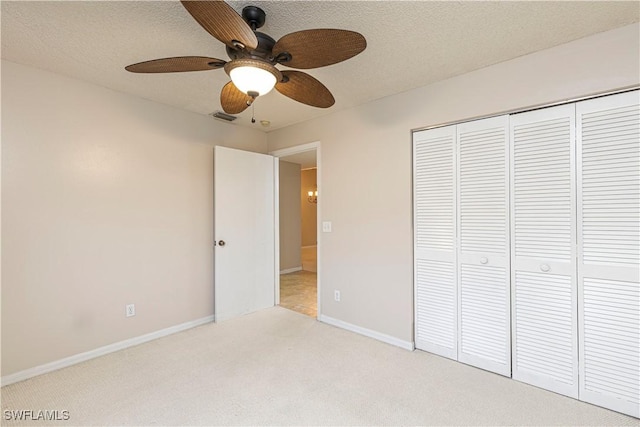 unfurnished bedroom featuring light carpet, a textured ceiling, ceiling fan, and a closet