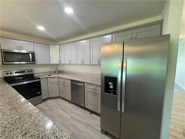 kitchen with light stone counters, sink, and stainless steel appliances