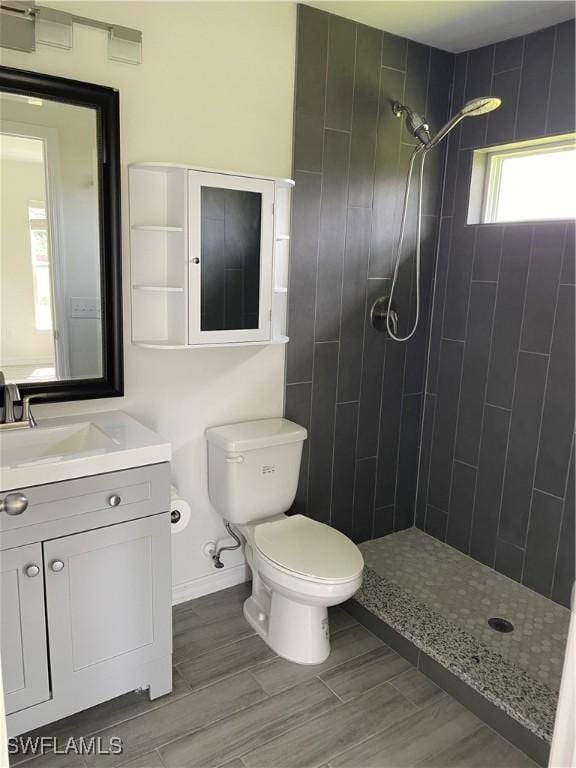 bathroom with vanity, toilet, and a tile shower