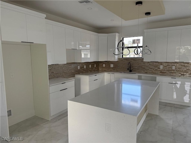 kitchen with white cabinets, a center island, sink, and decorative backsplash