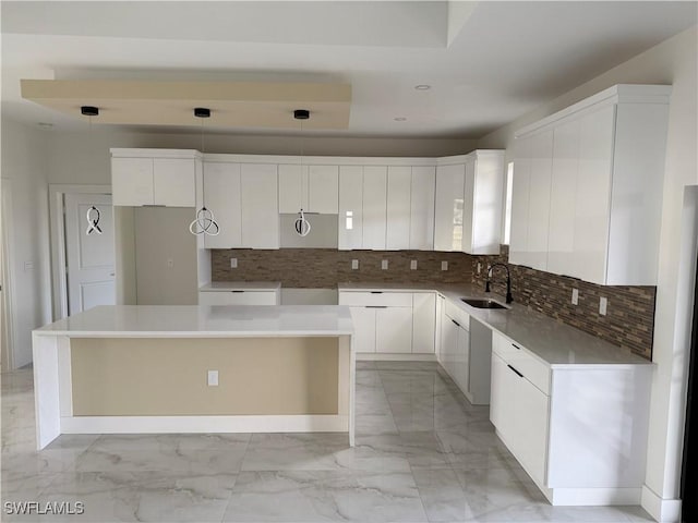 kitchen featuring sink, a center island, white cabinetry, and decorative light fixtures