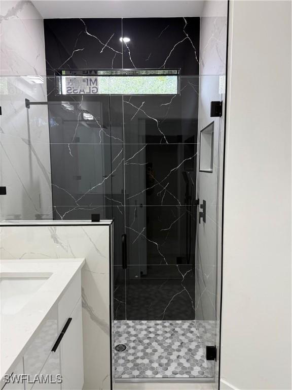 bathroom featuring a shower with shower door and vanity