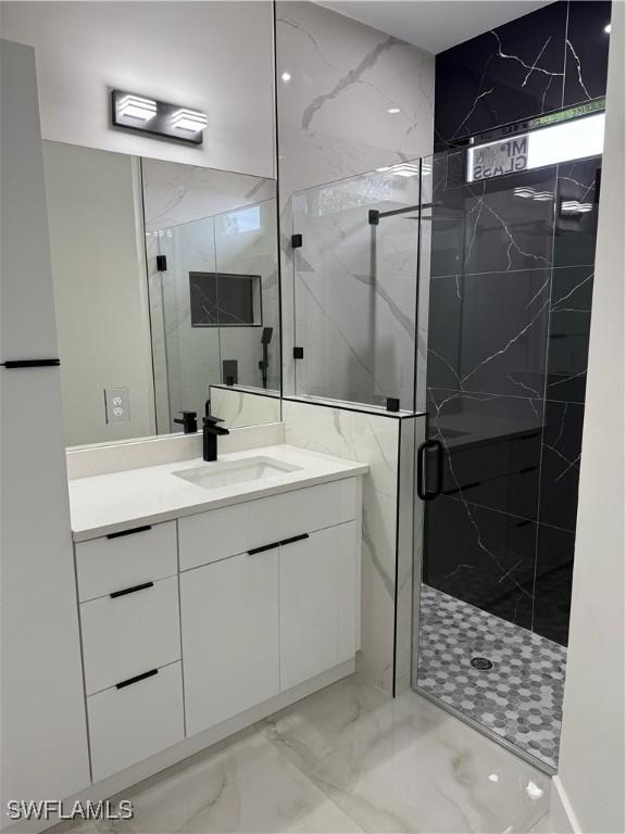 bathroom featuring a shower with shower door and vanity