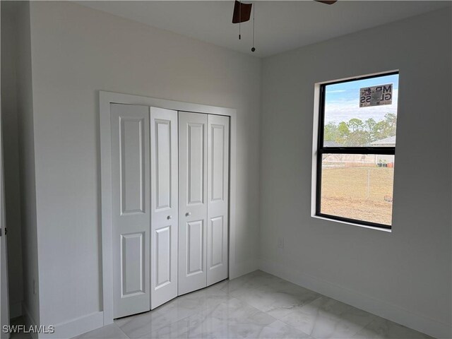 unfurnished bedroom featuring ceiling fan, a closet, and multiple windows