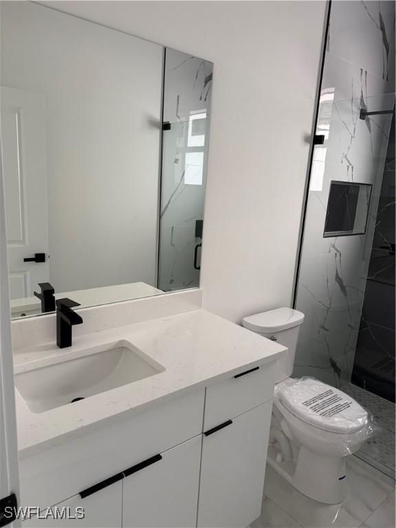 bathroom with a tile shower, vanity, and toilet