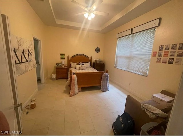 bedroom with ceiling fan, a tray ceiling, and light tile patterned floors