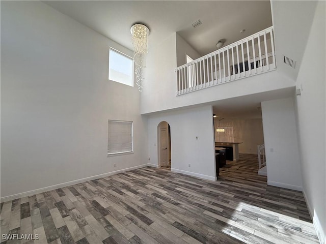 unfurnished living room with a towering ceiling and hardwood / wood-style flooring