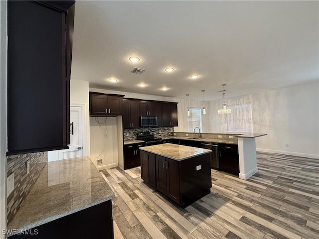 kitchen featuring black appliances, hanging light fixtures, a kitchen island, sink, and dark brown cabinets