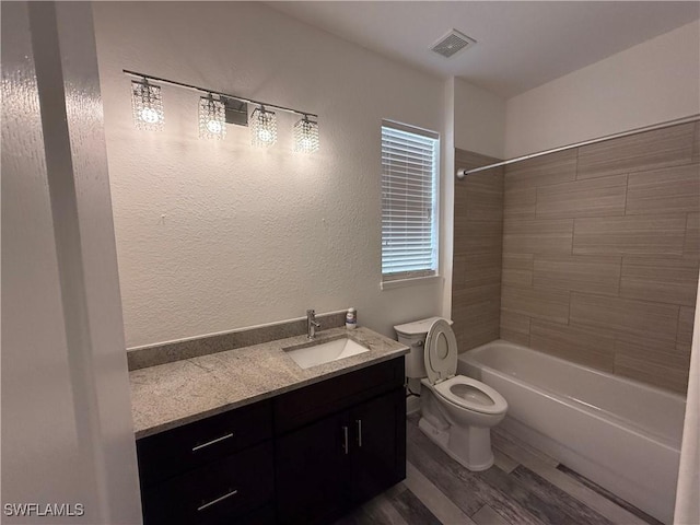 full bathroom featuring toilet, tiled shower / bath combo, wood-type flooring, and vanity