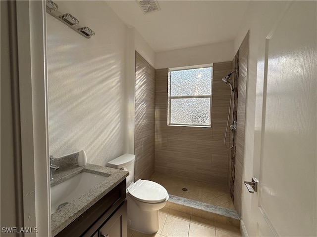 bathroom with tile patterned floors, a tile shower, vanity, and toilet