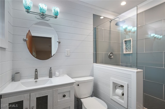 bathroom with a tile shower, vanity, and toilet