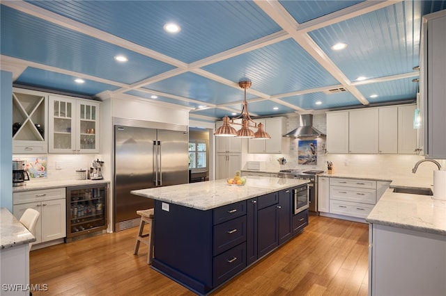 kitchen with stainless steel appliances, sink, decorative light fixtures, a center island, and beverage cooler