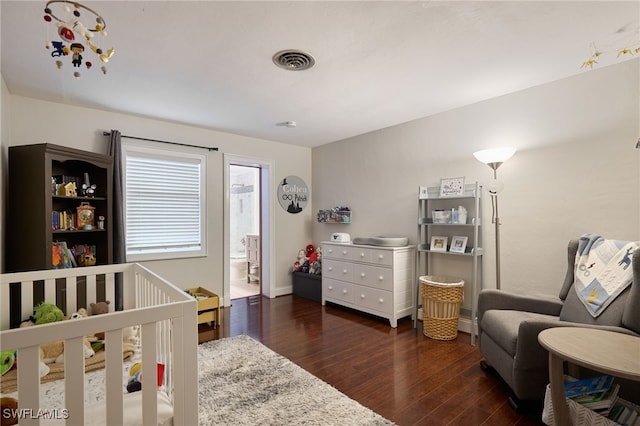 bedroom with a nursery area and dark wood-type flooring