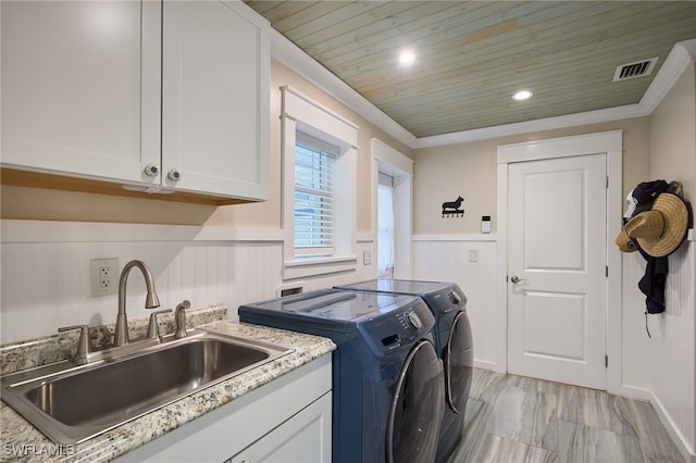 clothes washing area with cabinets, sink, ornamental molding, washer and dryer, and wooden ceiling