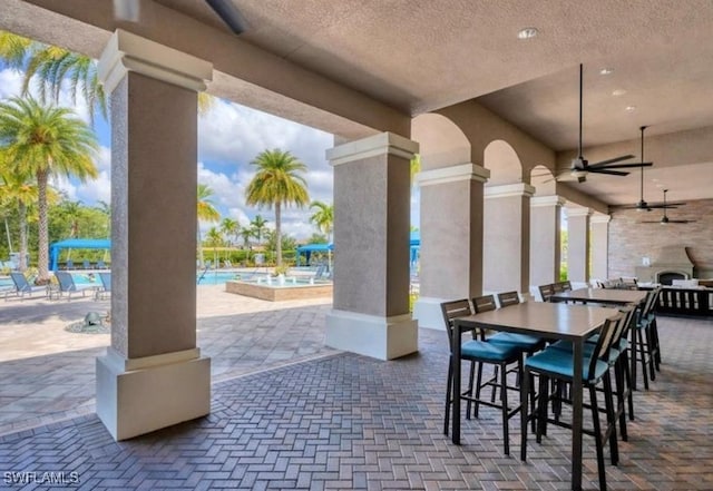 view of patio / terrace with ceiling fan, a community pool, and a bar