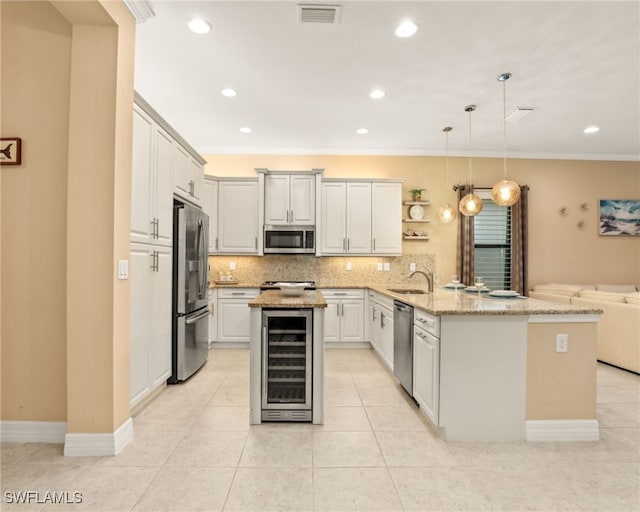 kitchen with appliances with stainless steel finishes, a center island, beverage cooler, hanging light fixtures, and sink