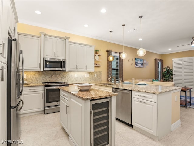 kitchen with kitchen peninsula, appliances with stainless steel finishes, beverage cooler, hanging light fixtures, and a center island