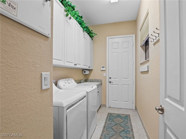 laundry area featuring washing machine and dryer, cabinets, light tile patterned flooring, and sink