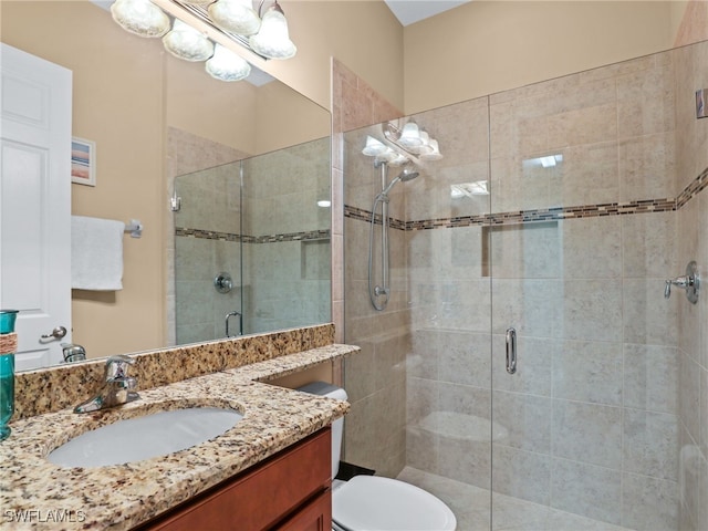 bathroom featuring a shower with shower door, vanity, and toilet