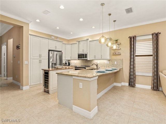 kitchen featuring backsplash, pendant lighting, kitchen peninsula, appliances with stainless steel finishes, and light stone counters