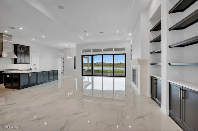 unfurnished living room with a notable chandelier, recessed lighting, a fireplace, a sink, and marble finish floor