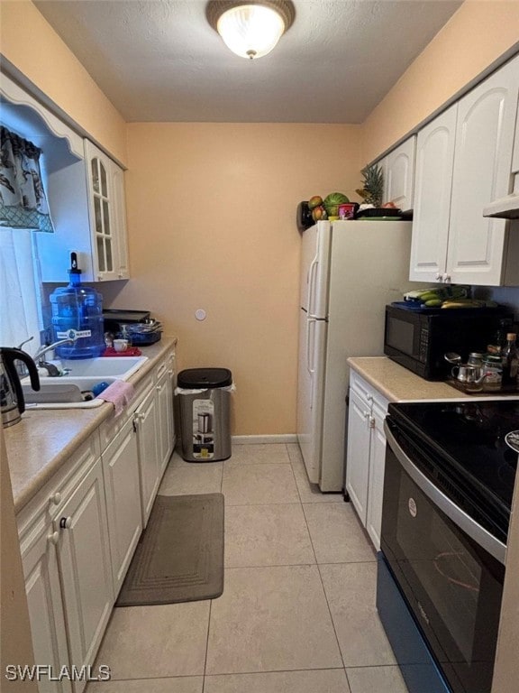 kitchen with sink, white refrigerator, white cabinetry, light tile patterned flooring, and electric range