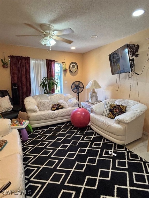 living room with ceiling fan, tile patterned flooring, and a textured ceiling