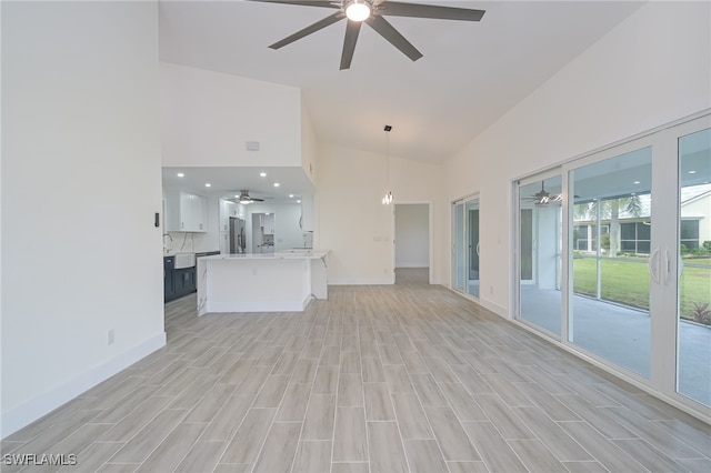 unfurnished living room featuring high vaulted ceiling and light hardwood / wood-style floors