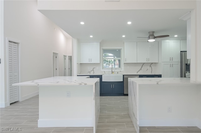 kitchen featuring light stone countertops, white cabinetry, tasteful backsplash, and sink