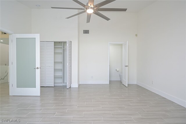 unfurnished bedroom featuring ceiling fan, a closet, and a high ceiling