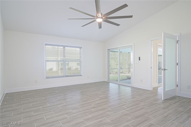 empty room with lofted ceiling, ceiling fan, and a healthy amount of sunlight