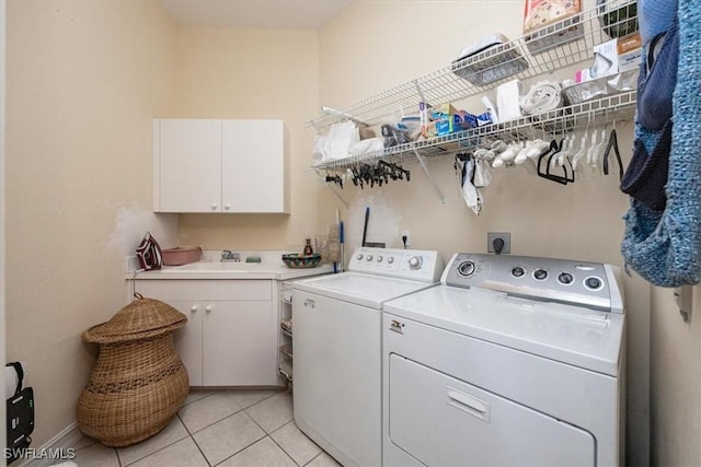 laundry area featuring light tile patterned floors, sink, washer and clothes dryer, and cabinets