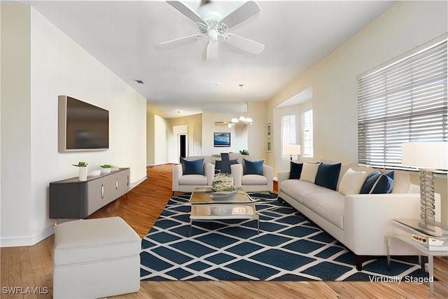 living room with wood-type flooring and ceiling fan with notable chandelier