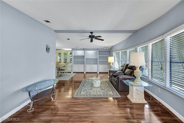 living room with ceiling fan, a healthy amount of sunlight, dark wood-type flooring, and a textured ceiling