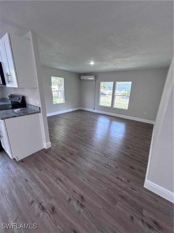 unfurnished living room with a wall mounted AC and dark wood-type flooring