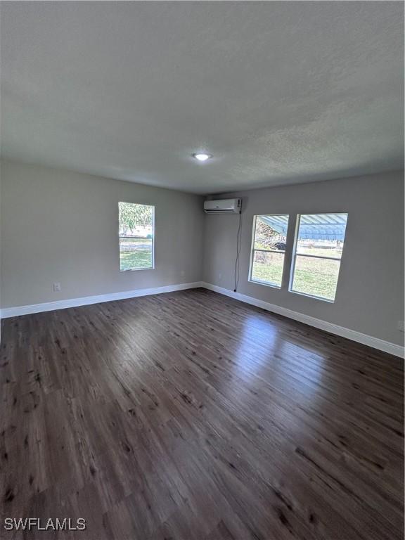 unfurnished room featuring dark wood-type flooring and a wall unit AC